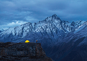 Dianne Mao, "Solitude Beneath The Giants" - A photograph of a camping tent perched on a cliff near the Himalayan mountains.