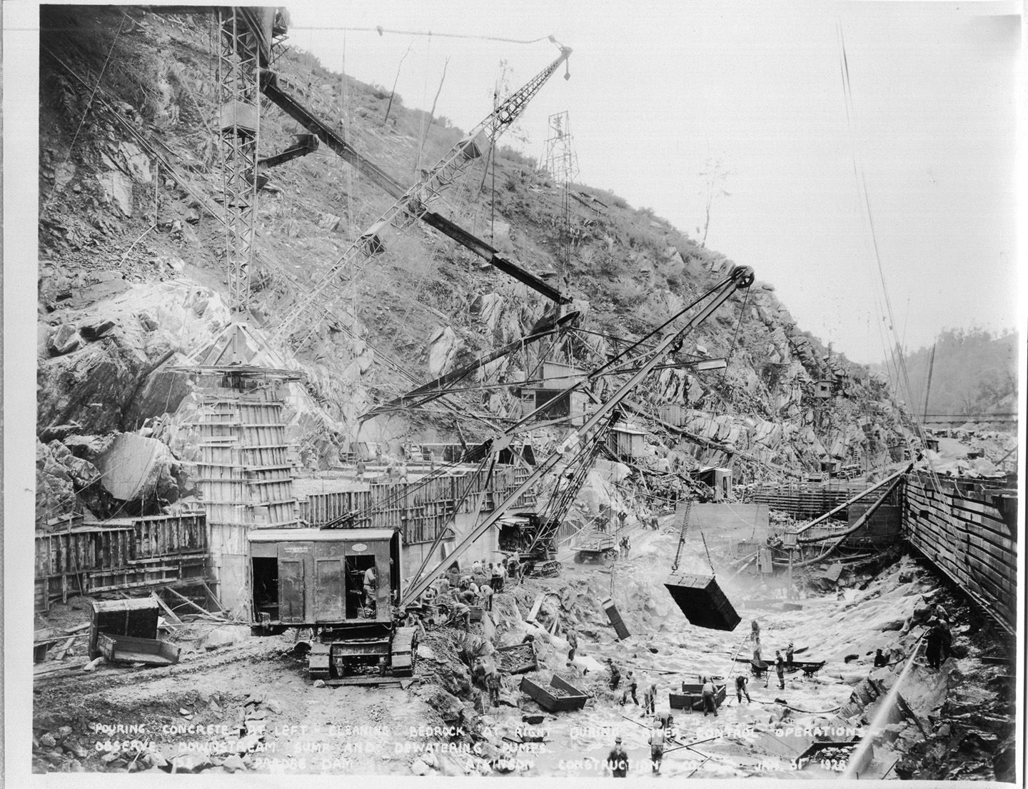 Pouring concrete at left - cleaning bedrock at right during river control operations. Observe downstream sump and dewatering pumps. (January 1928)