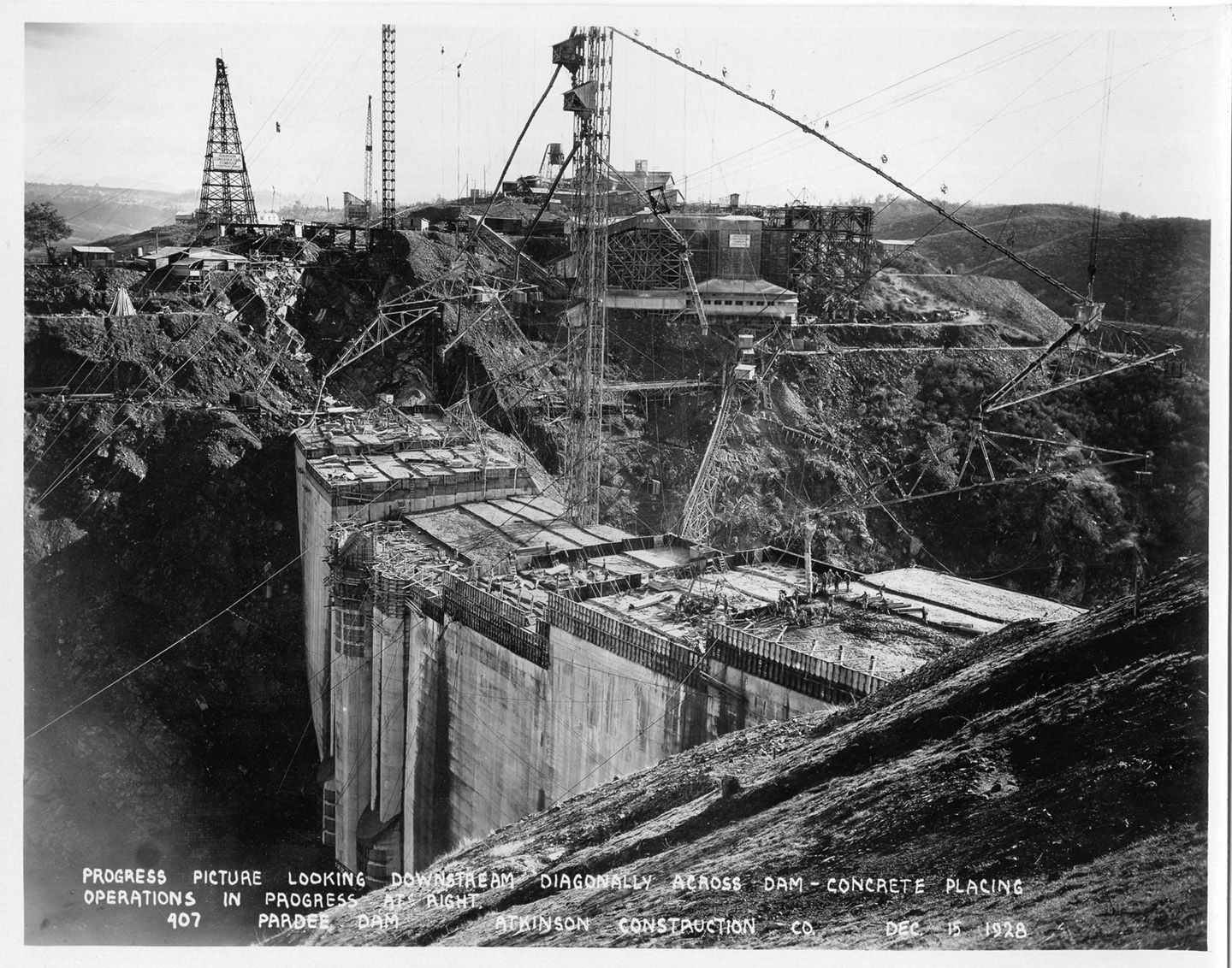 Progress picture looking downstream diagonally across dam - concrete placing operations in progress at right. (December 1928)