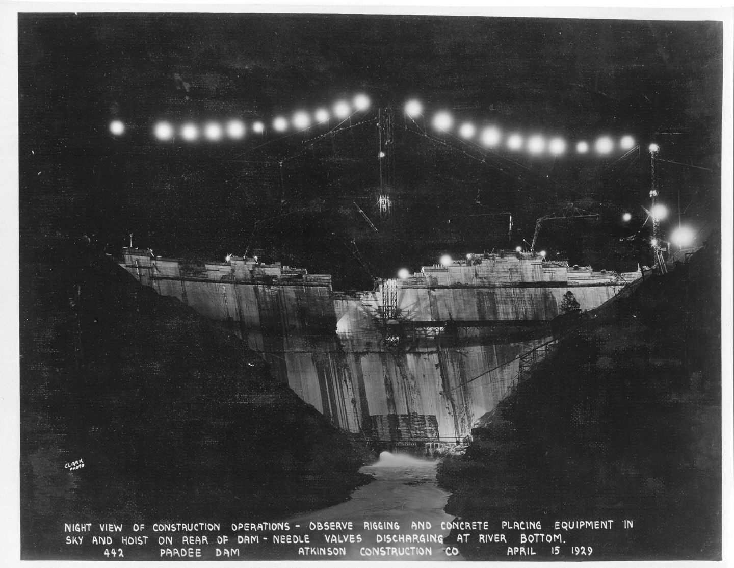 Night view of construction operations - observe rigging and concrete placing of equipment in sky an hoist on rear of dam - needle valves discharging at river bottom. (April 1929)